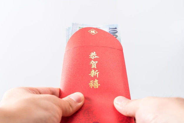 Man's hand holding with Chinese red envelope (red packet). Chinese new year concept.( Chinese "GÅnghÃ¨ xÄ«nxÇ" on it means "Wish you prosperity")