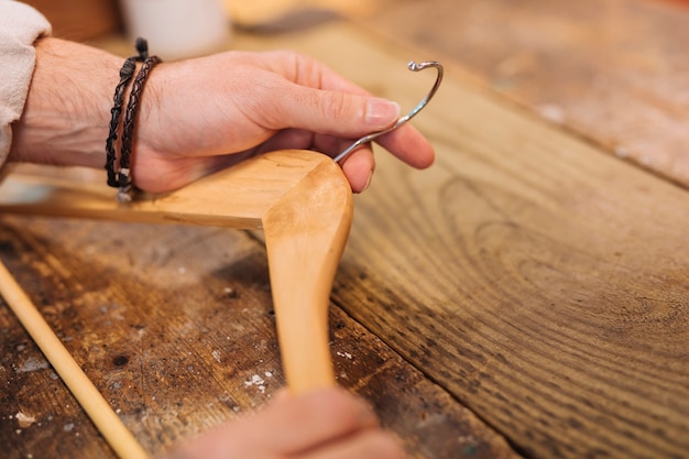 La mano dell'uomo che tiene il gancio di legno sulla tavola di legno nel deposito dei vestiti
