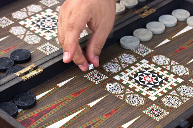 A man's hand holds a backgammon game