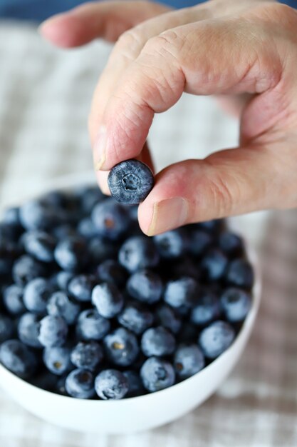 A man's hand holds blueberries.