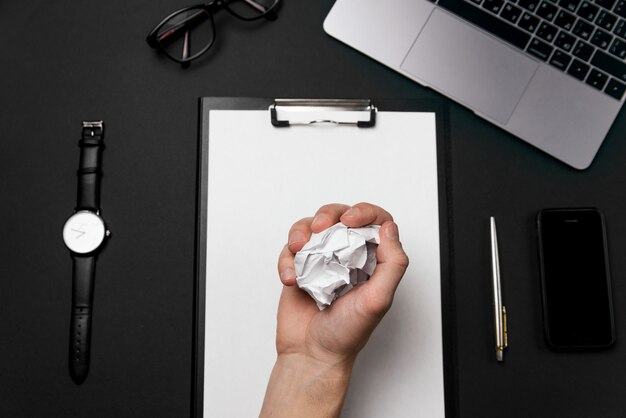 The man's hand holds the crumpled paper.