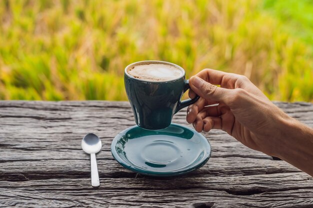 A man's hand holds a cup of coffee on the background of an old wooden table. A heart for coffee. St. Valentine's Day concept.