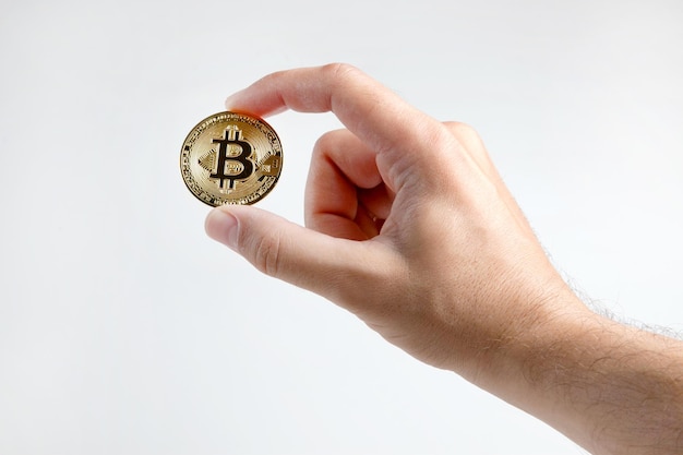 La mano di un uomo tiene un bitcoin d'oro isolato su uno sfondo bianco