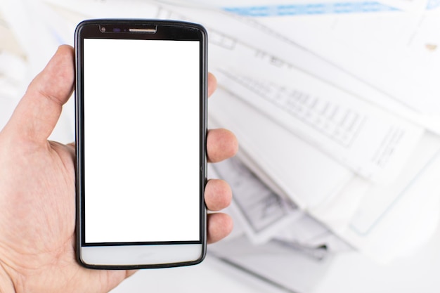 La mano di un uomo tiene un telefono cellulare su uno sfondo di mockup di documenti sparsi