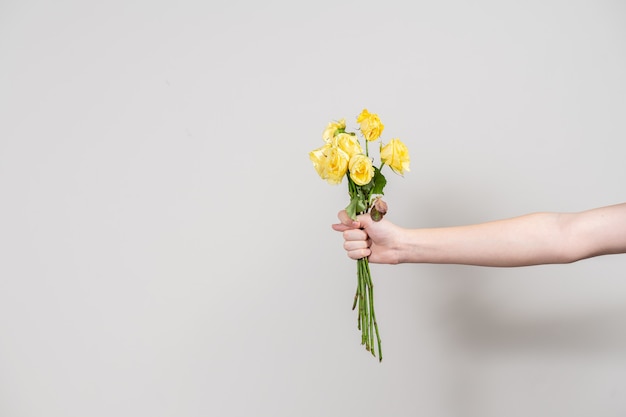 The man's hand holds out a bouquet of wilted flowers and shows a fig. separation concept. layout with place for text