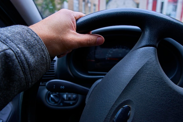 A man's hand holds the steering wheel of a car