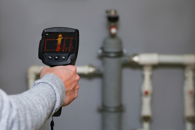 Photo a man's hand holds a thermal imager, checking the heating system of a house.