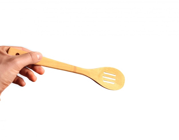 A man's hand holds a wooden spoon-spatula isolated on a white background. Kitchen tools for cooking.