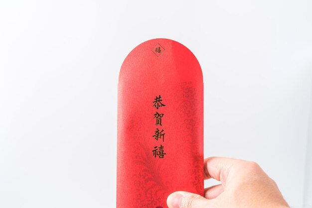 Man's hand houden met Chinese rode envelop (rood pakket). Chinees nieuwjaarsconcept (Chinees "GÅ nghÃ¨ xÄ«nxÇ" erop betekent "wens je welvaart")