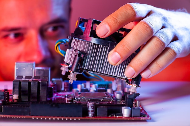 A man's hand inserts a cooler into the motherboard socket