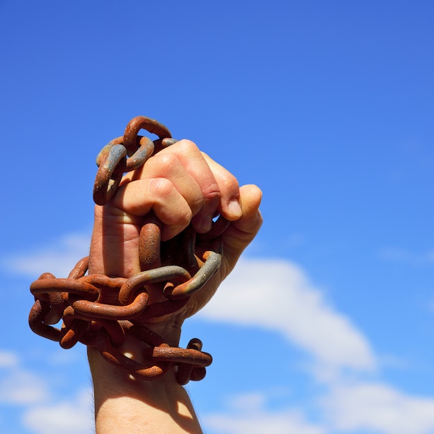 Man's hand is chained in iron chains 