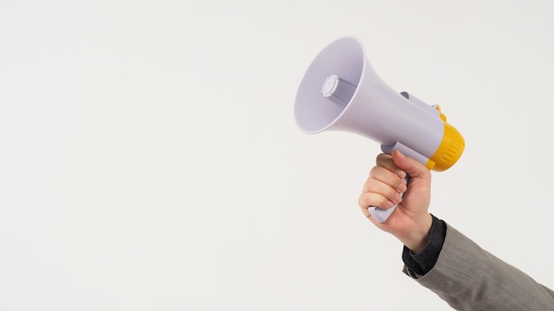 The man's hand is holding a megaphone and wears a grey suit on white background.