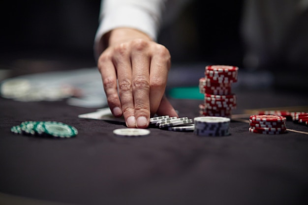 A man's hand is reaching for a poker chips.