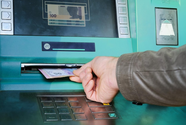 A man's hand is takeing money in an ATM.