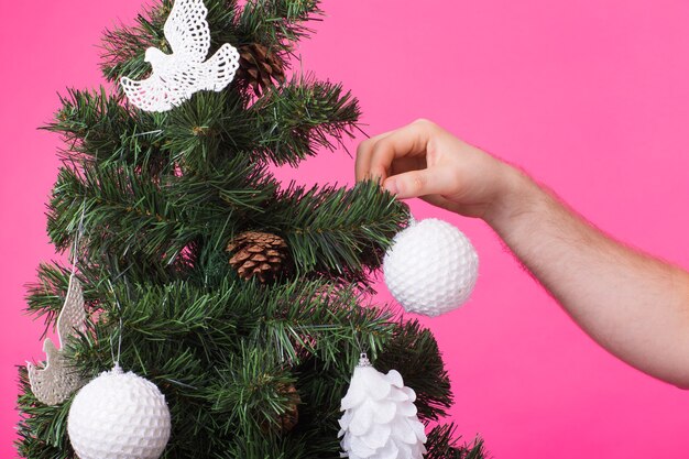 Man's hand kerstboom versieren op roze