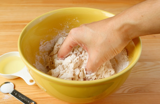 Man's hand kneading bread dough in the mixing bowl