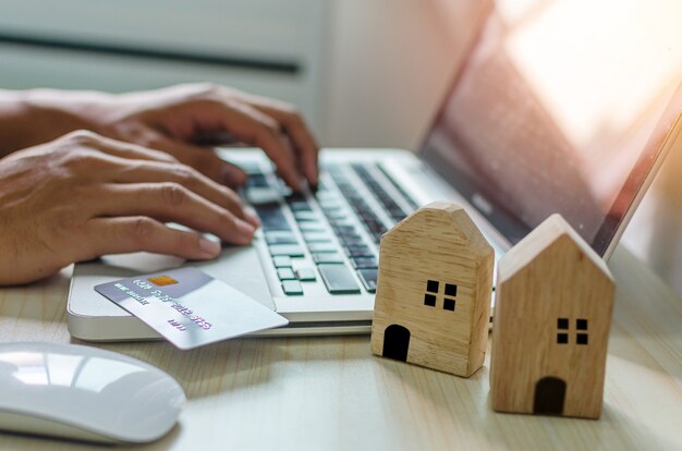 Man's hand looking for business, credit card and home loan information with a laptop computer at his desk