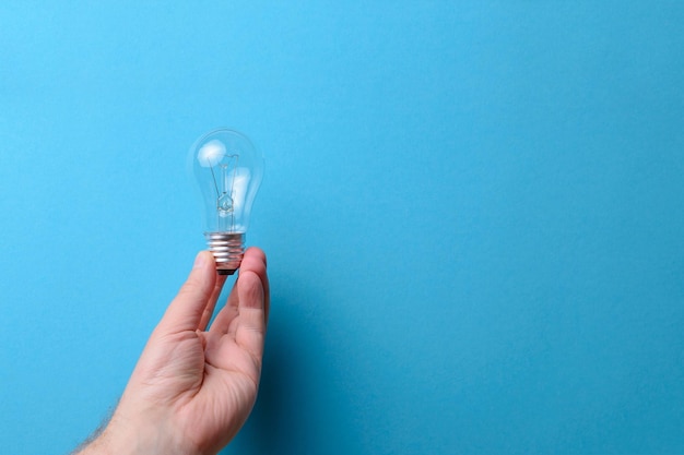 Man's hand met een gloeilamp blauwe achtergrond ruimte voor tekst