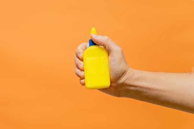 Man's hand met gele buis op oranje achtergrond