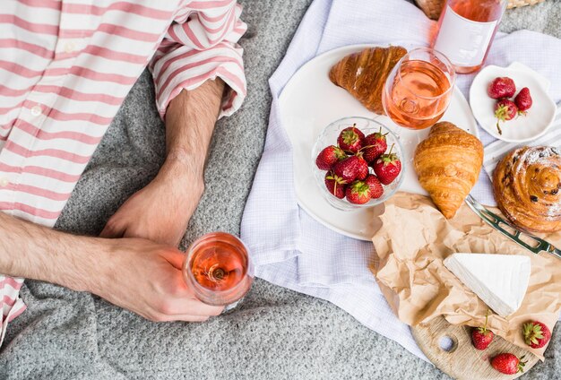 Man's hand met glas rose wijn zomerpicknick met kaas en wijn