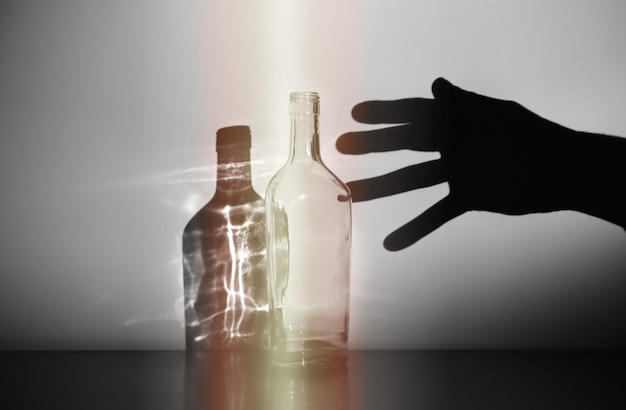 Man's hand met het silhouet van de alcoholfles. Alcohol verslaafde. Gevaarlijke gewoonte. Ongezond leven concept. Sociaal probleem.