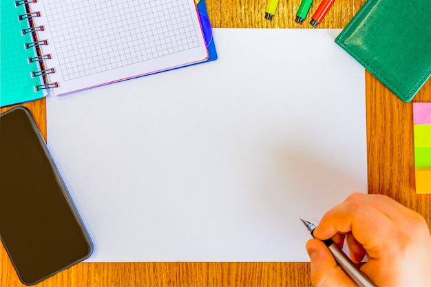 Man's hand met pen schrijven op het Witboek (concept). Man aan het bureau met behulp van telefoon, notitieblok, pen, viltstift, dagboek. Plannen maken. Werk organisatie.