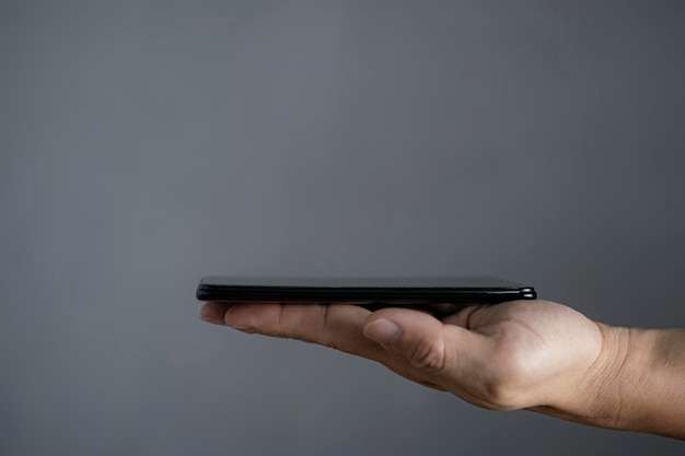 Man's hand met smartphotne scherm naar boven geïsoleerd op een grijze achtergrond