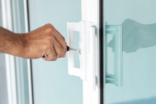 Foto mano d'uomo che apre una porta a vetri con una chiave