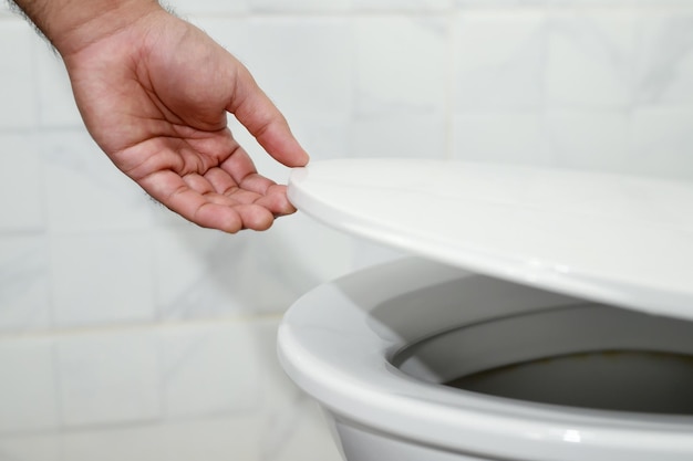 Man's hand opening the toilet lid