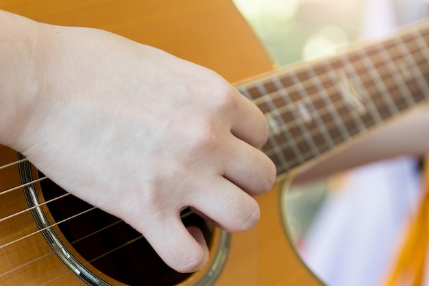 Man's hand playing acoustic guitar , musical concept