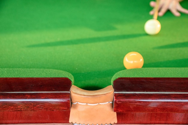 Man's hand playing snooker in bar with color snooker ball