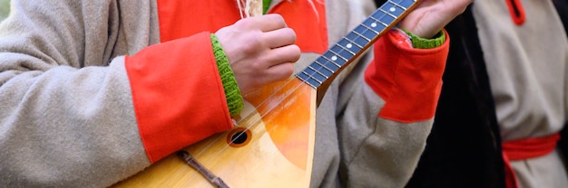 A man's hand plays the balalaika. male musician with a traditional Russian musical instrument in winter Russian folk national clothes.  