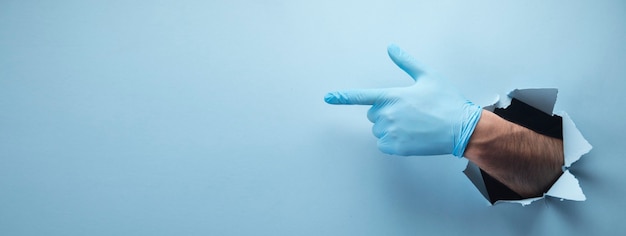 Man's hand points a finger in a glove on a blue scene