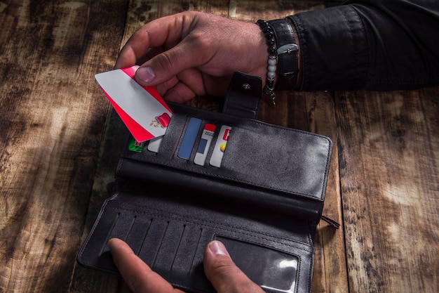 Man's hand pulls out a credit card from a black purse