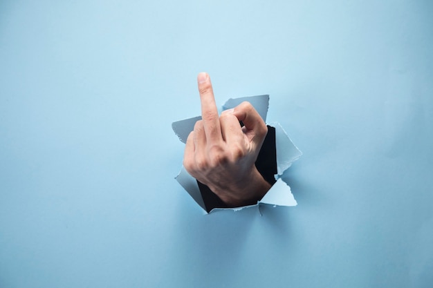 Man's hand showing middle finger on blue scene