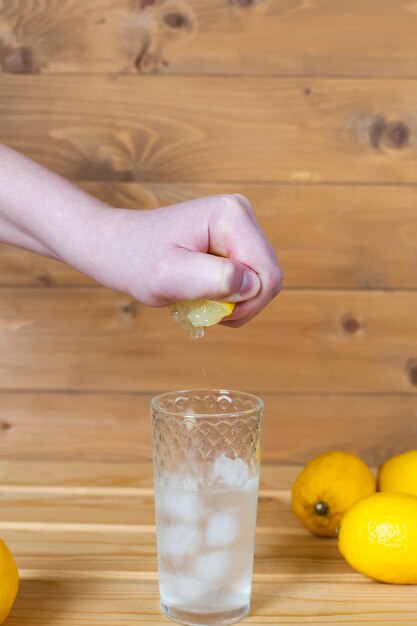 Man's hand squeezing half a lemon into a bowl.