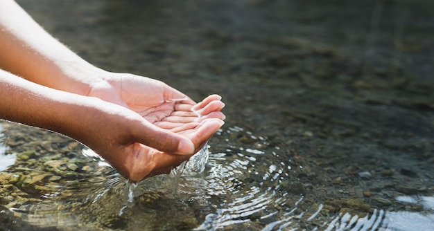 Man's hand touching water in the midst of nature