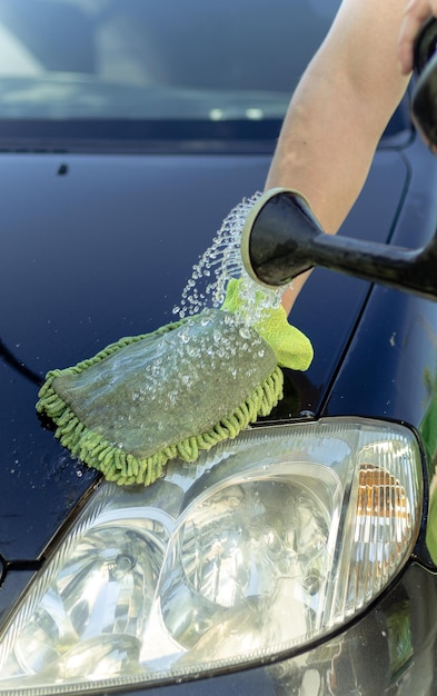 男の手が繊維布で車を洗う