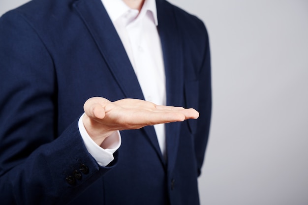 Man's hand wearing suit showing a sign at studio