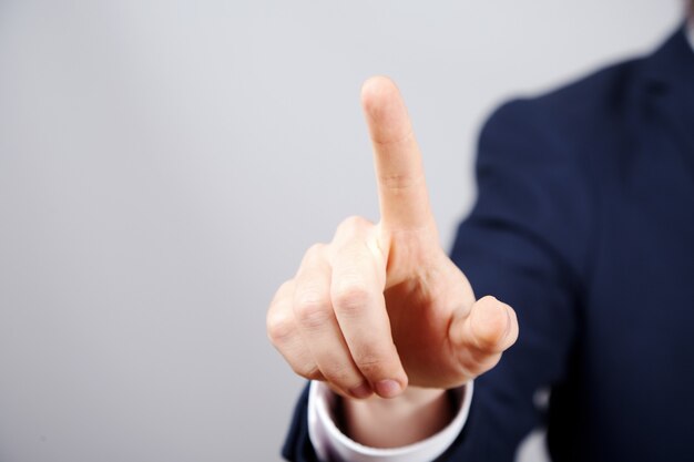 Man's hand wearing suit showing a sign at studio