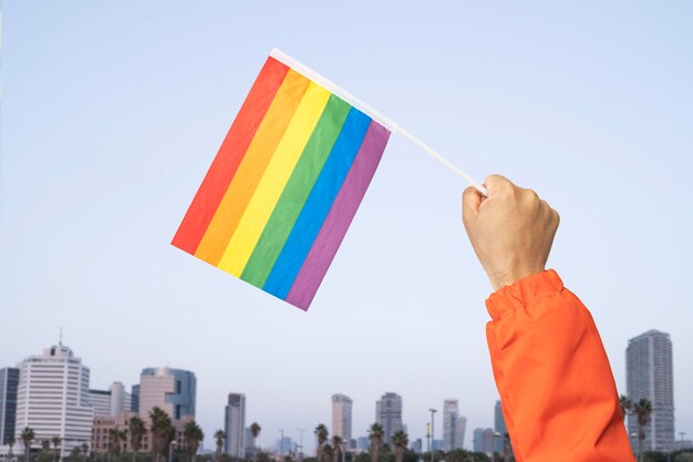 La mano dell'uomo con la bandiera lgbt alla parata dell'orgoglio lotta per i tuoi diritti