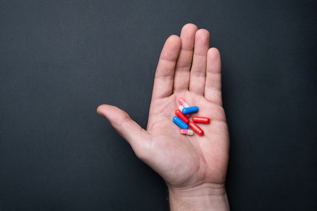 Man's hand with medicine on a black background. Treatment of a coronavirus, flu , or cold. Medical concept