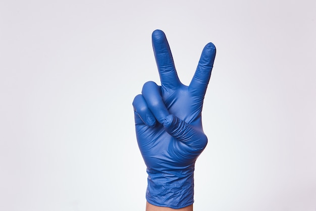 Man's hand with nitrile gloves for medicine making gesture of victory