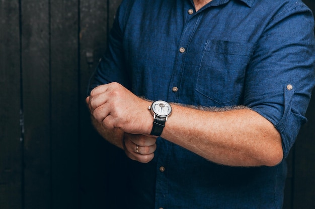 A man\'s hand with a watch businessman a business man fastens\
his watch on a dark background