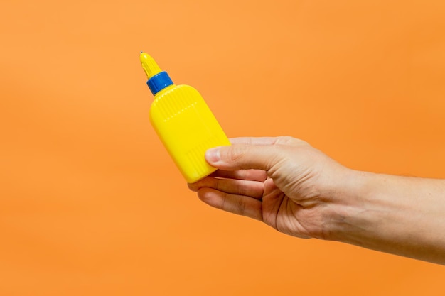 Man's hand with yellow tube on orange background