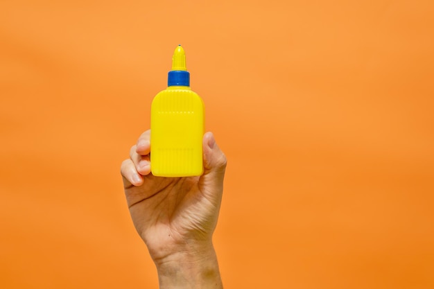 Man's hand with yellow tube on orange background