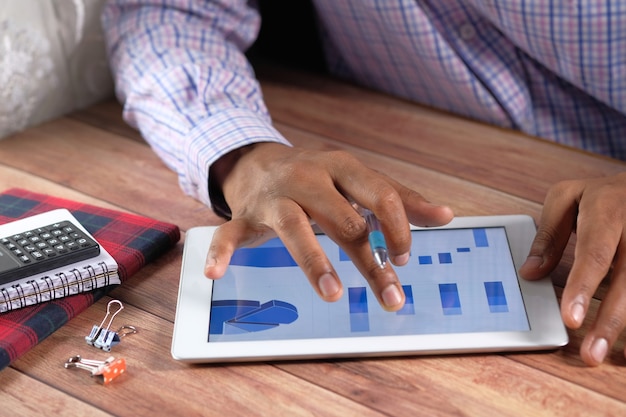 man's hand working on digital tablet at office desk, using self created chart