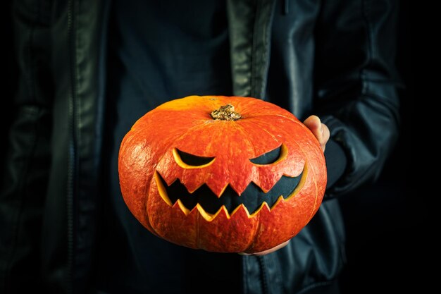 man's hands are holding carved glowing pumpkin with a creepy face Halloween concept