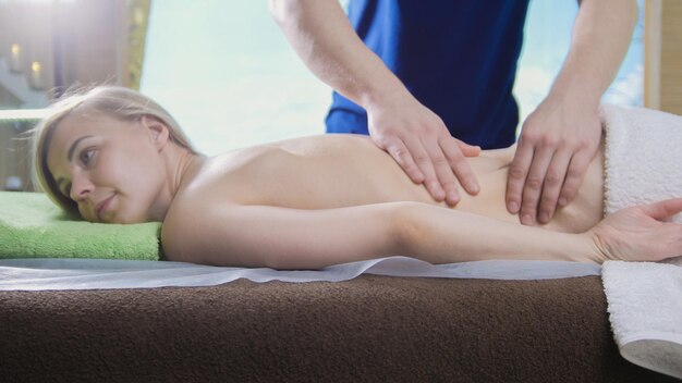 Man's hands on the back of the girl in massage parlor, close up