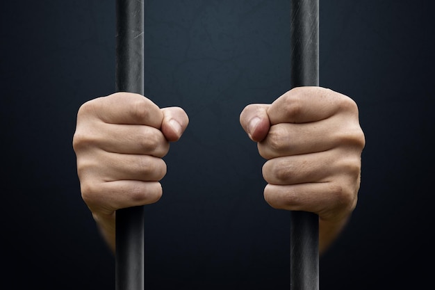 Man\'s hands behind bars justice punishment imprisonment court\
prison